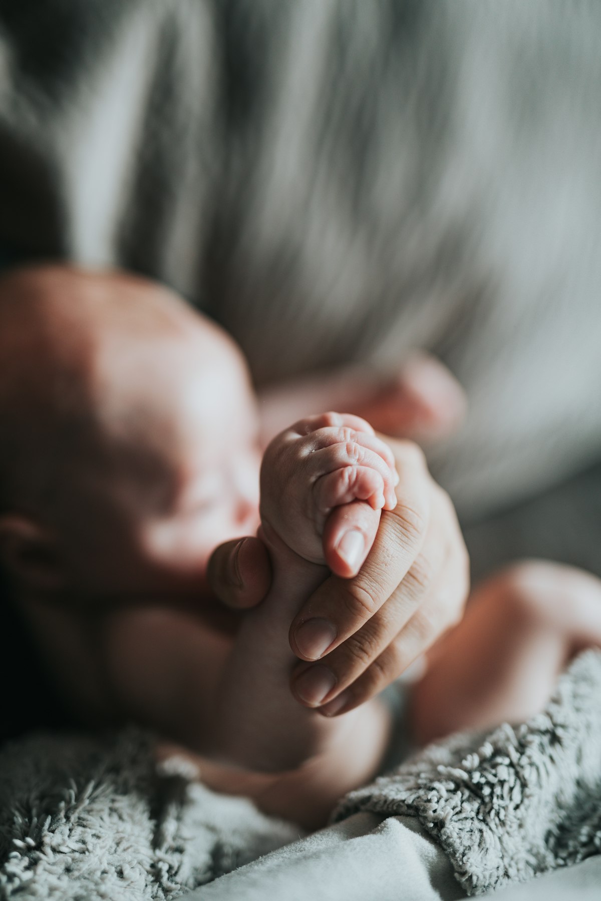 A newborn's hand holding a parent's finger